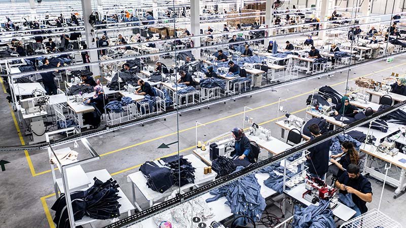 A clothing artisan sewing a garment in a clean, modern factory