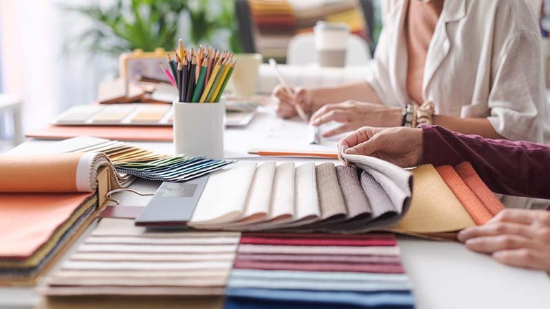 Finding Fabric Suppliers a person looking through a large book of fabric swatches