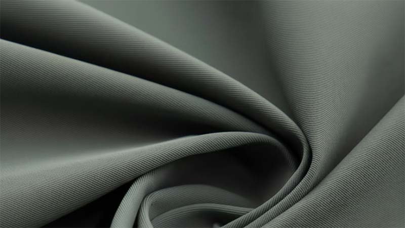 Sourcing Activewear Fabrics a hand holding and stretching a piece of high-performance activewear fabric