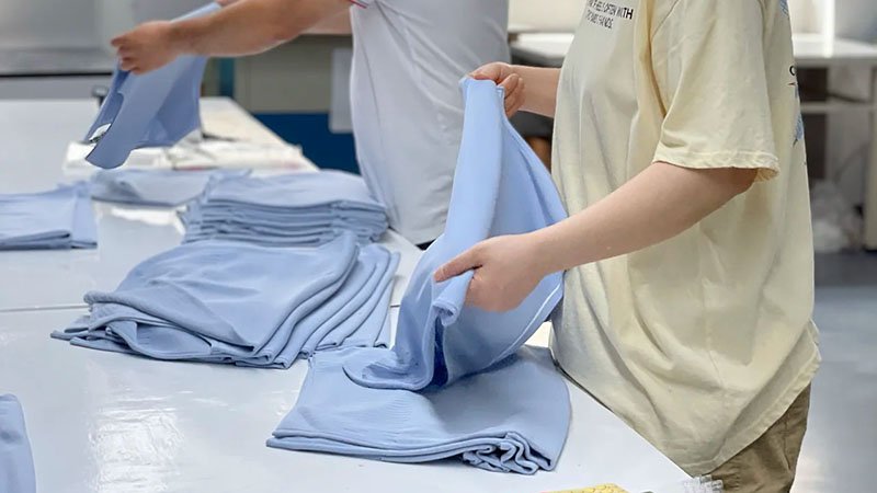 a quality control inspector measuring a finished sports garment