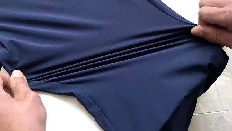 Testing Activewear Fabric Quality a person stretching a fabric swatch to test its elasticity