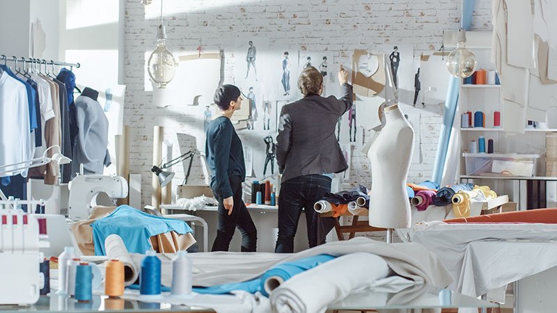 a designer and a factory manager collaborating over a tech pack