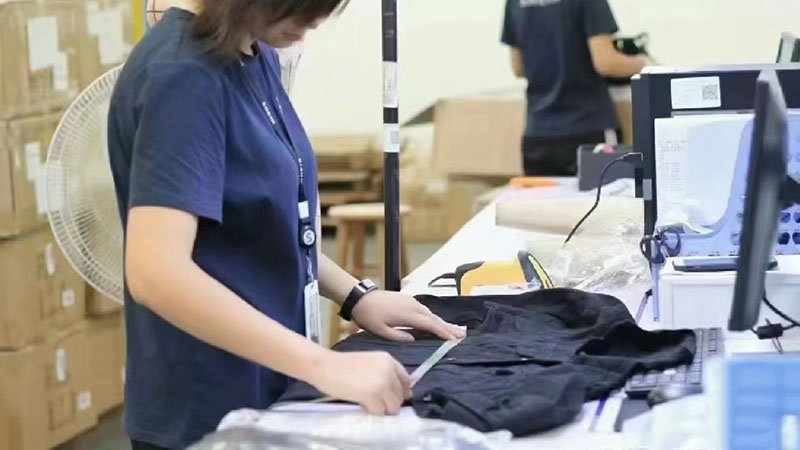 an inspector checking the stitching on a garment with a magnifying glass
