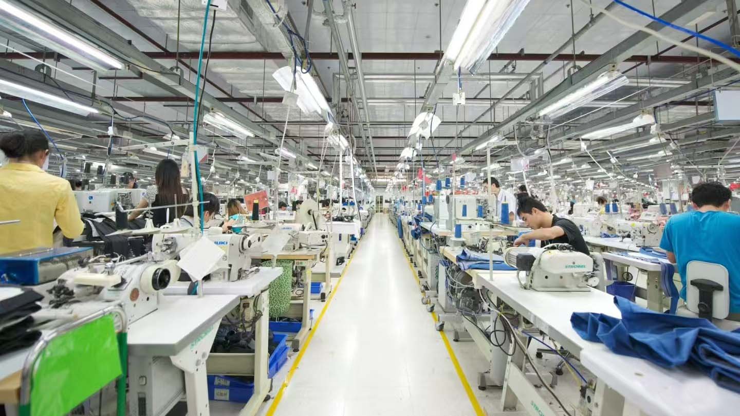 a person inspecting a sportswear garment on a factory line
