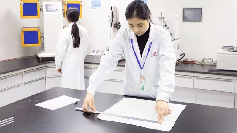 Fabric Quality Control Process A quality control inspector comparing a bulk fabric roll to a master sample swatch