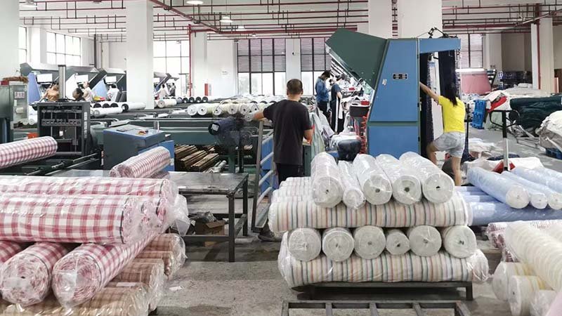 Why Manufacturers Have MOQs a factory worker setting up a large fabric roll on an industrial cutting machine